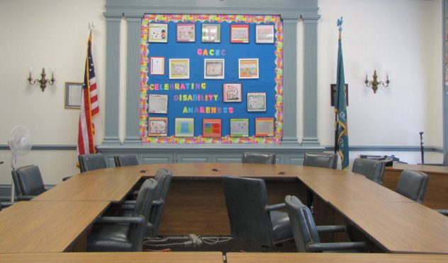 2011 DHAM Bulletin Board on the back wall inside a room with the American and Delaware flags, chairs and tables